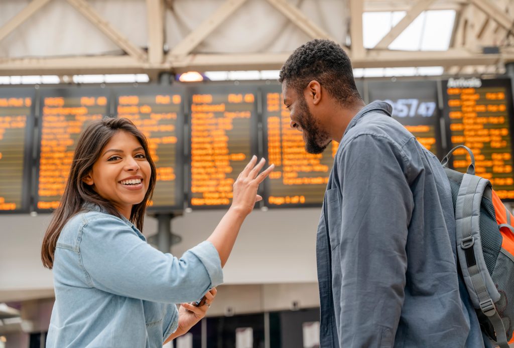 young family couple at the train station exited about oncoming travel in front of timetable